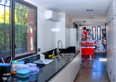 Vista de la cocina comedor común. Mobiliario de color rojo y lockers a los costados.