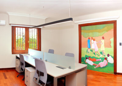 Interior de oficina con escritorio dividido con vidrio. Cuadro colorido en una de las paredes.