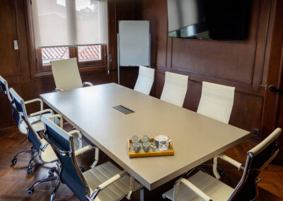 Interior de la sala de reuniones con mesa larga y sillas.
